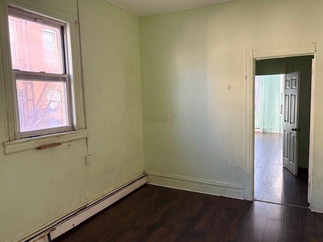 spare room with dark hardwood / wood-style flooring and a baseboard radiator