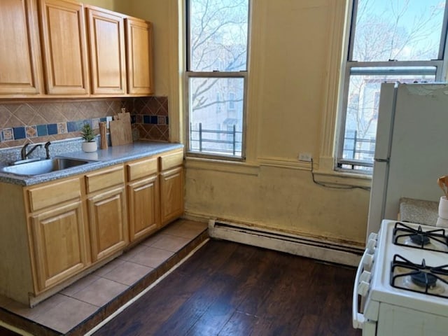 kitchen featuring baseboard heating, a wealth of natural light, sink, and white appliances