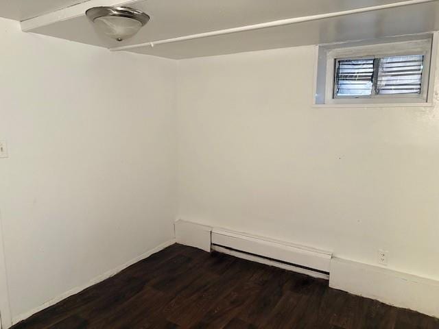 unfurnished room with baseboard heating and dark hardwood / wood-style floors