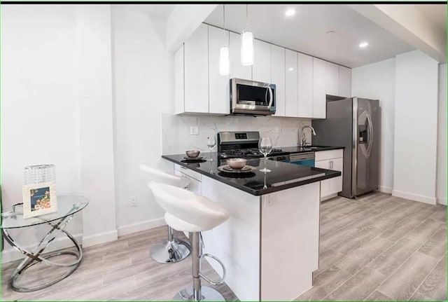 kitchen featuring white cabinets, modern cabinets, hanging light fixtures, stainless steel appliances, and backsplash