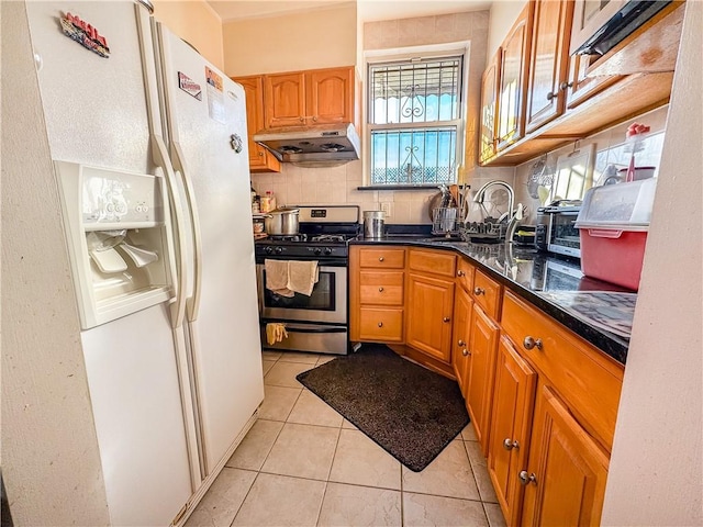 kitchen with sink, gas range, tasteful backsplash, light tile patterned floors, and white refrigerator with ice dispenser