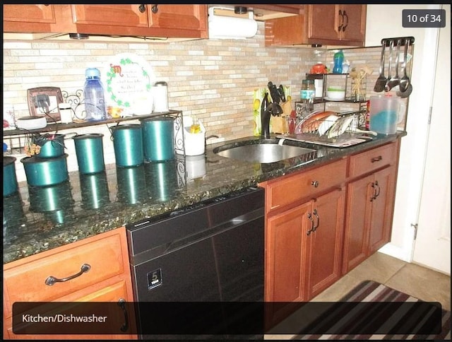 kitchen featuring black dishwasher, tasteful backsplash, dark stone counters, and sink