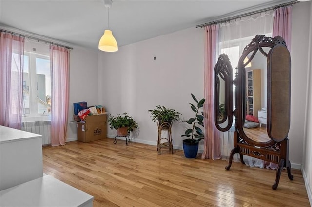 sitting room with radiator, baseboards, and light wood-style floors