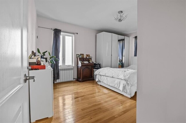 bedroom with light hardwood / wood-style floors and radiator