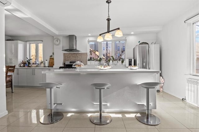 kitchen featuring recessed lighting, wall chimney range hood, radiator heating unit, stainless steel electric stove, and light tile patterned flooring