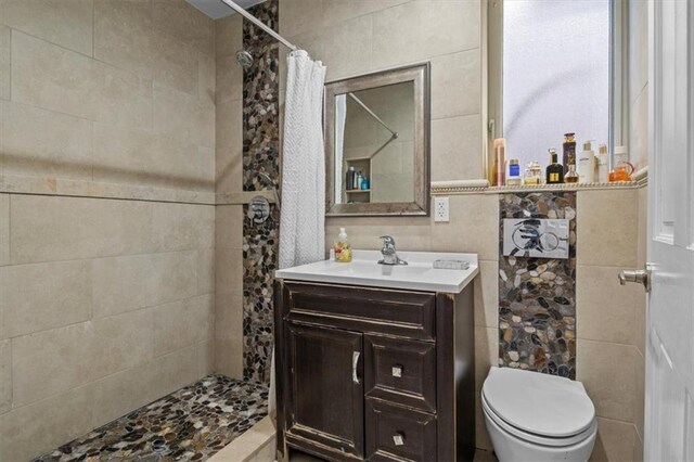 bathroom featuring toilet, a shower with shower curtain, tile walls, and vanity