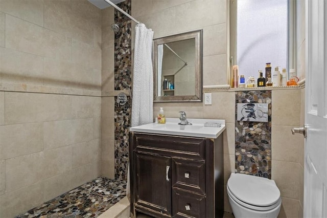 bathroom with vanity, toilet, curtained shower, and tile walls