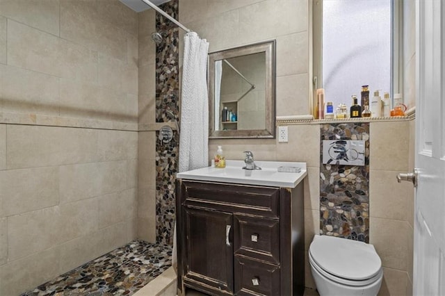 full bath with toilet, a tile shower, and vanity