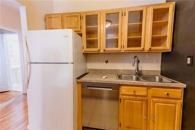 kitchen with white fridge, decorative backsplash, light wood-type flooring, dishwasher, and sink