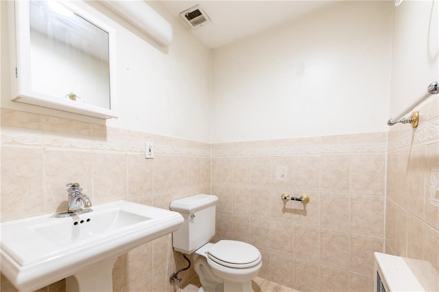 bathroom with toilet, tile walls, and sink