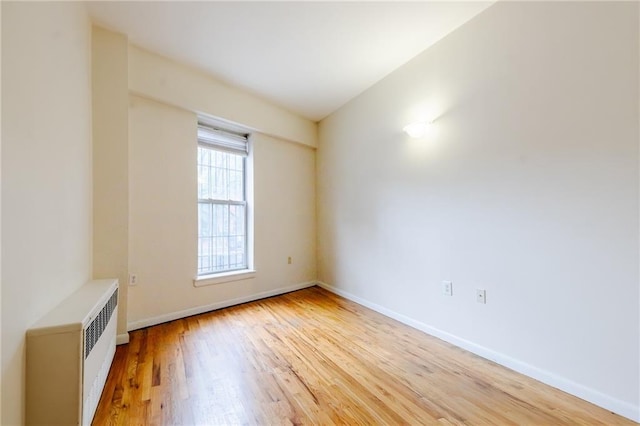 empty room with light hardwood / wood-style floors and radiator heating unit