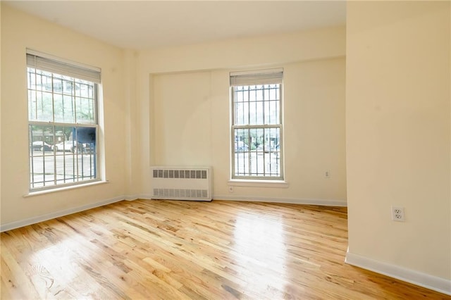 empty room featuring light hardwood / wood-style floors, a wealth of natural light, and radiator heating unit