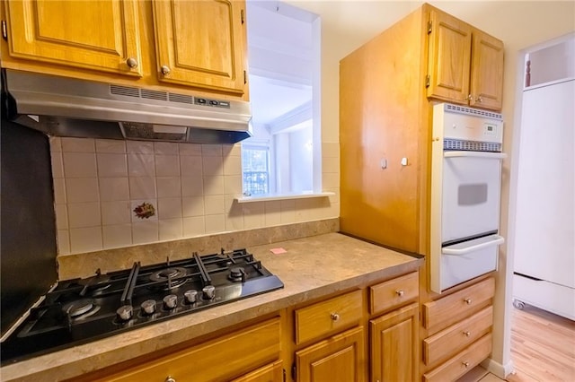 kitchen with black gas cooktop, backsplash, and oven