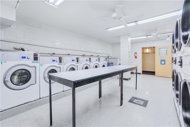 community laundry room with a ceiling fan, stacked washer and clothes dryer, washer and dryer, and concrete block wall