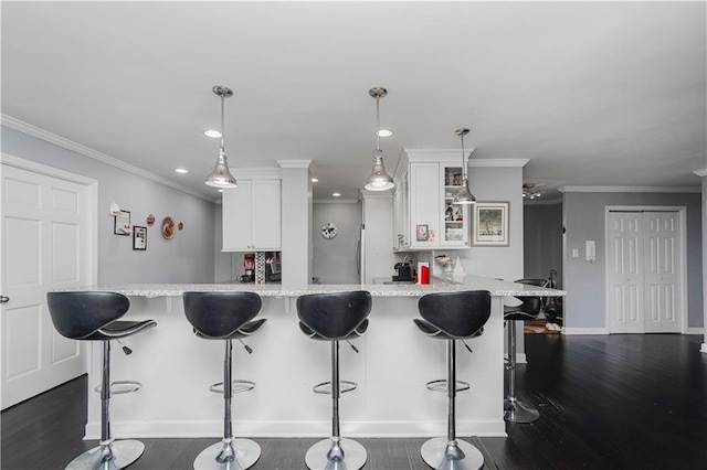 kitchen featuring a kitchen breakfast bar, white cabinetry, baseboards, ornamental molding, and glass insert cabinets