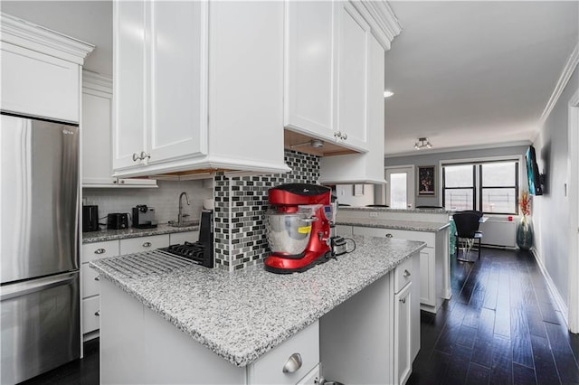 kitchen featuring light stone counters, freestanding refrigerator, white cabinets, and tasteful backsplash