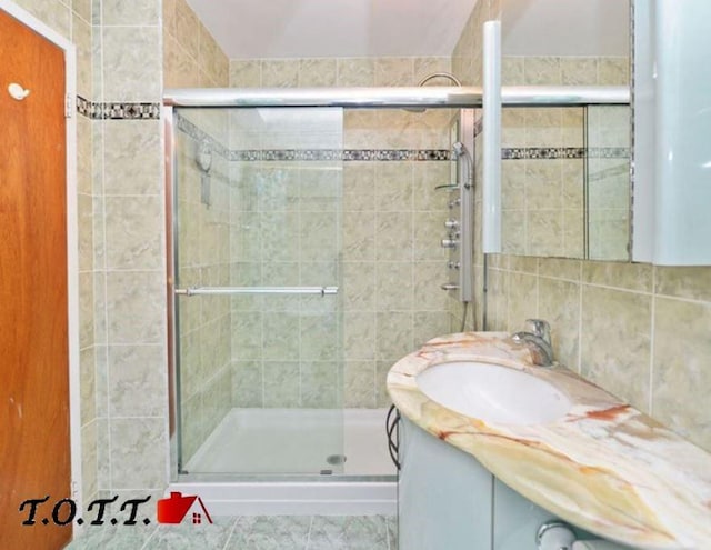 bathroom featuring a shower with shower door, vanity, and tasteful backsplash