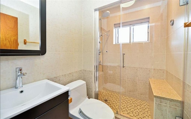 bathroom with toilet, a shower with shower door, decorative backsplash, tile walls, and vanity