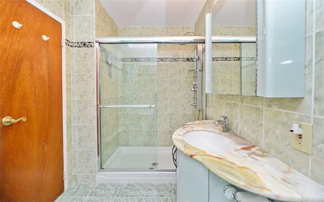 bathroom featuring vanity, tile walls, a shower with door, and decorative backsplash