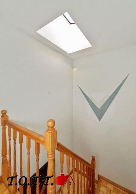 stairs featuring a skylight and parquet flooring