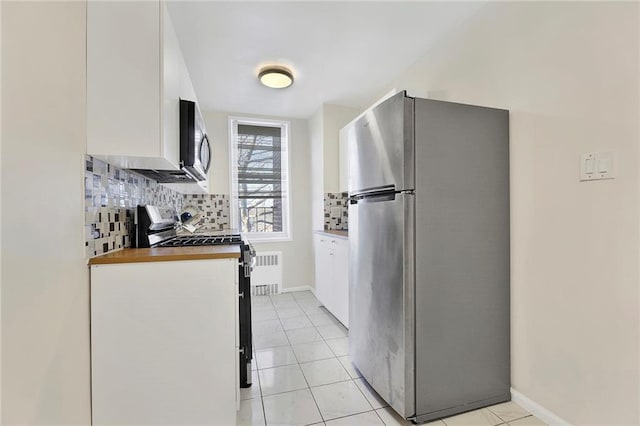 kitchen featuring tasteful backsplash, stainless steel appliances, light tile patterned flooring, and white cabinets