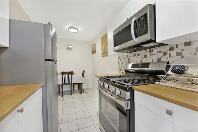 kitchen featuring light tile patterned flooring, appliances with stainless steel finishes, white cabinets, and decorative backsplash