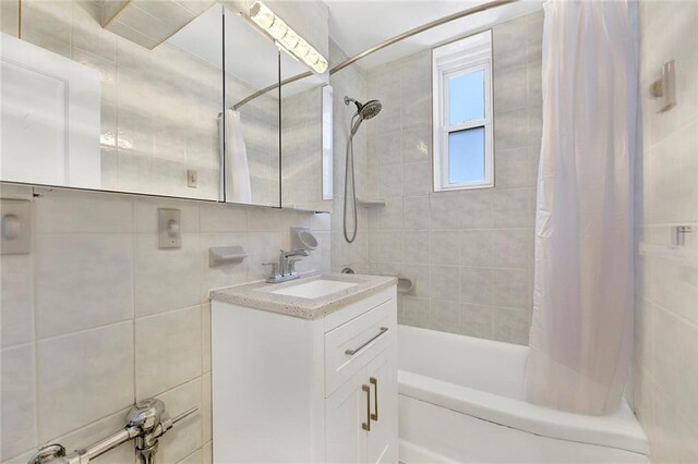 bathroom featuring shower / bath combo, tile walls, vanity, and backsplash