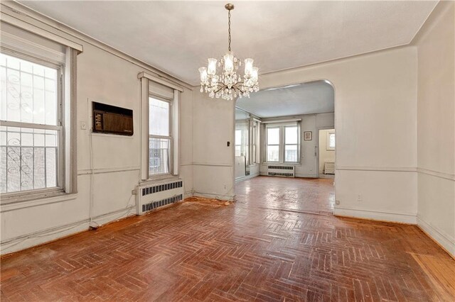 interior space featuring radiator, a notable chandelier, a wall unit AC, and parquet floors