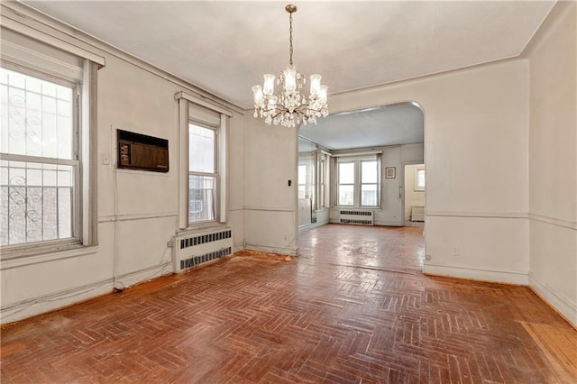 interior space with a notable chandelier, radiator heating unit, a wall unit AC, and parquet flooring