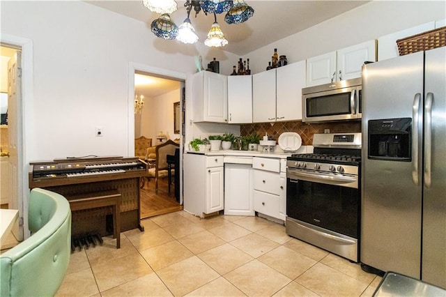 kitchen featuring appliances with stainless steel finishes, decorative light fixtures, white cabinetry, light tile patterned floors, and a chandelier