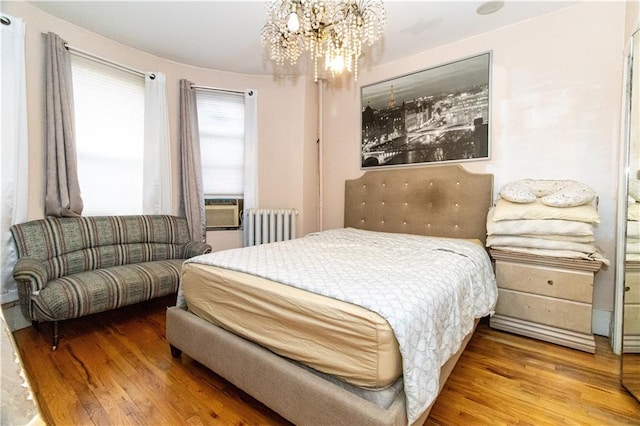 bedroom featuring hardwood / wood-style flooring, radiator heating unit, and a chandelier