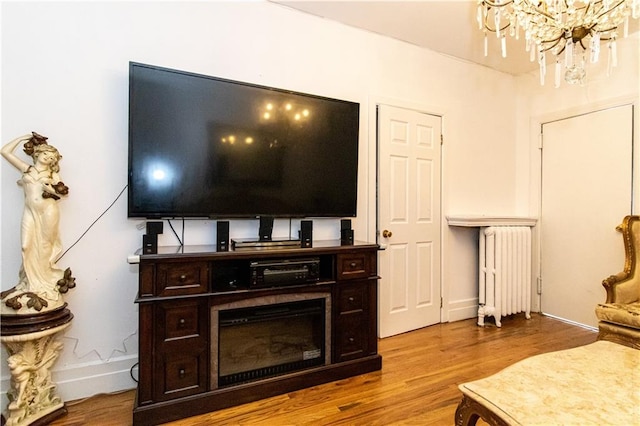 living room featuring light wood-type flooring, radiator, and a notable chandelier