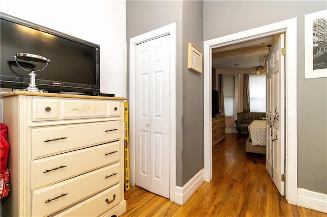 corridor with light wood finished floors and baseboards