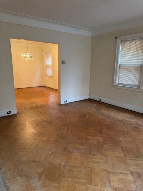 empty room featuring crown molding, parquet floors, and an inviting chandelier