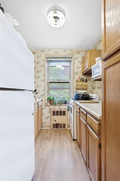 kitchen featuring light hardwood / wood-style floors and white appliances