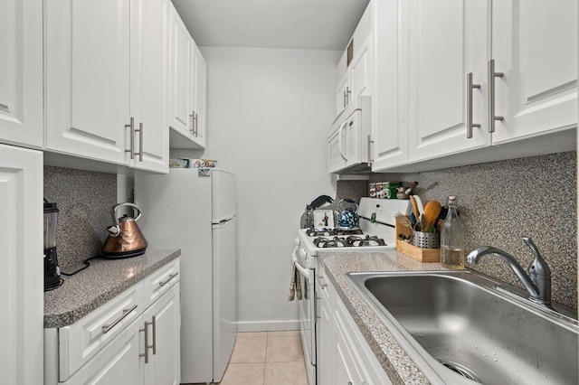 kitchen featuring light tile patterned floors, white appliances, a sink, white cabinetry, and backsplash