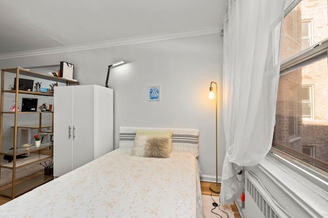 bedroom featuring baseboards, crown molding, radiator heating unit, and wood finished floors