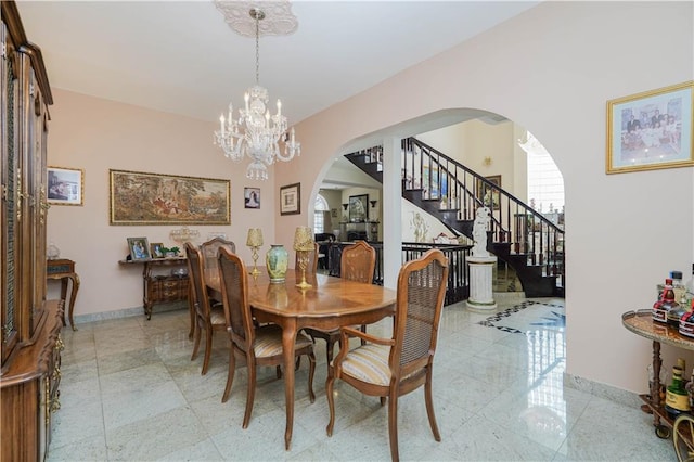 dining area featuring arched walkways, baseboards, stairs, and an inviting chandelier