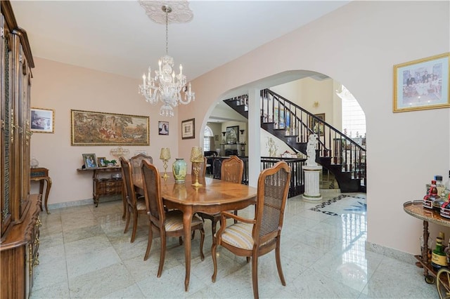 dining space featuring arched walkways, baseboards, stairs, and a chandelier