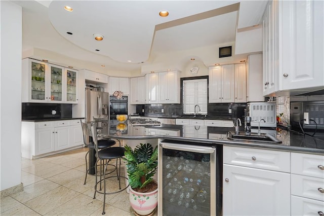 kitchen with dark countertops, tasteful backsplash, wine cooler, and white cabinets