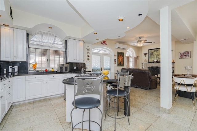 kitchen with dark countertops, a breakfast bar, a wall unit AC, and tasteful backsplash