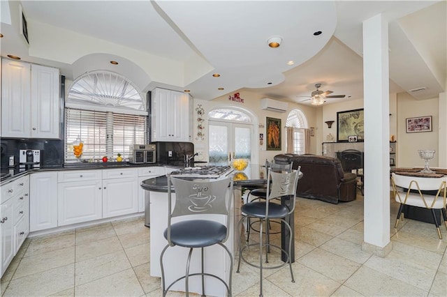 kitchen with ceiling fan, a kitchen bar, dark countertops, tasteful backsplash, and an AC wall unit