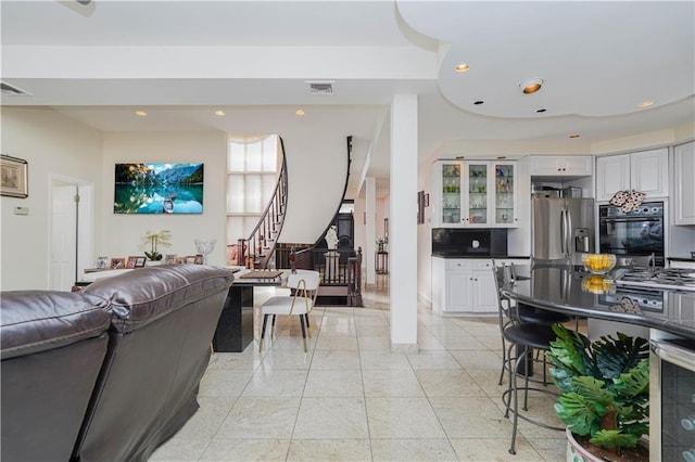 living room with recessed lighting, visible vents, light tile patterned flooring, and stairway