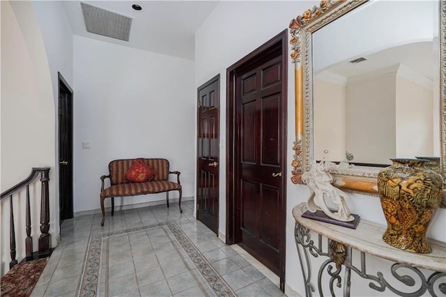 hall featuring ornamental molding, visible vents, baseboards, and light tile patterned floors