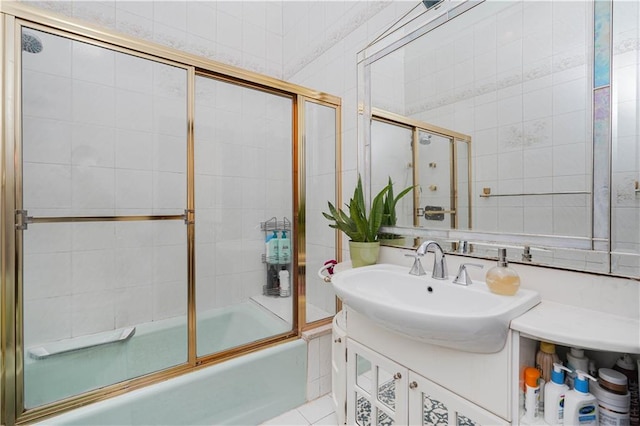 full bath featuring vanity, combined bath / shower with glass door, and tile walls