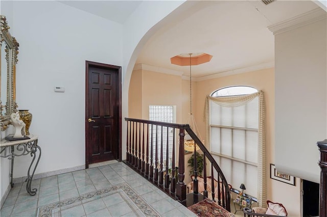 corridor featuring arched walkways, baseboards, ornamental molding, and light tile patterned flooring