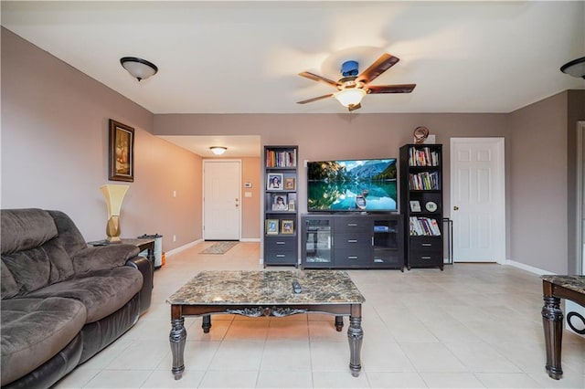 living area featuring light tile patterned floors, a ceiling fan, and baseboards