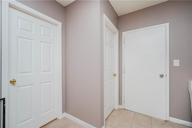 hallway with light tile patterned floors and baseboards