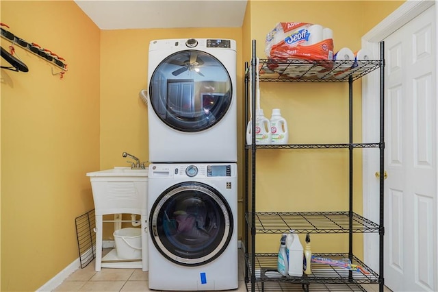 laundry area featuring baseboards, tile patterned flooring, stacked washer and clothes dryer, and laundry area