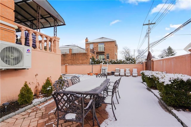 snow covered patio featuring fence, ac unit, and outdoor dining space